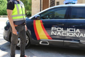 Agente de la Policía Nacional junto a un coche patrulla